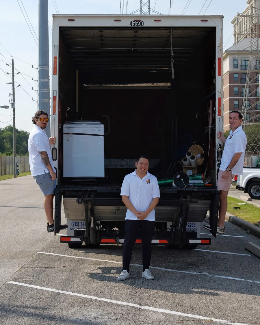 Stack Haus Movers crew at the back of their open box truck in a Houston parking lot