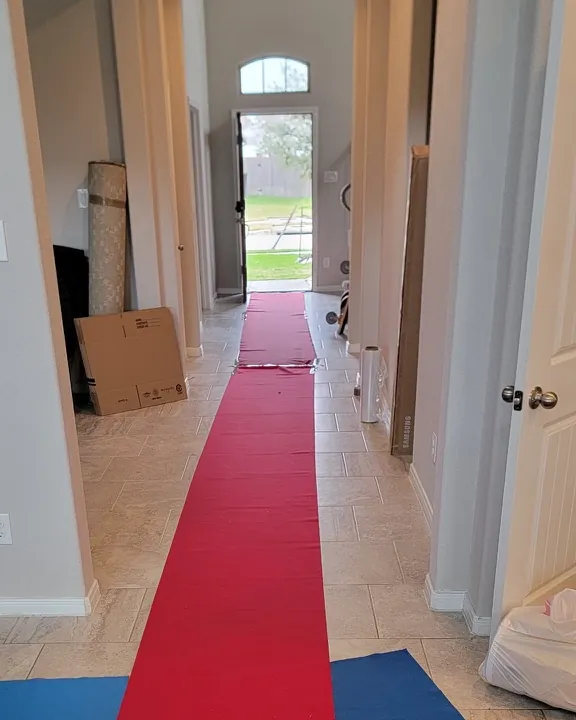 Red and blue floor runners laid down a hallway from the front door of a home