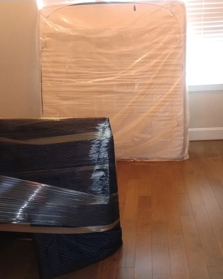 Bedroom furniture padded with moving blankets and a mattress in a plastic mattress bag, ready to move